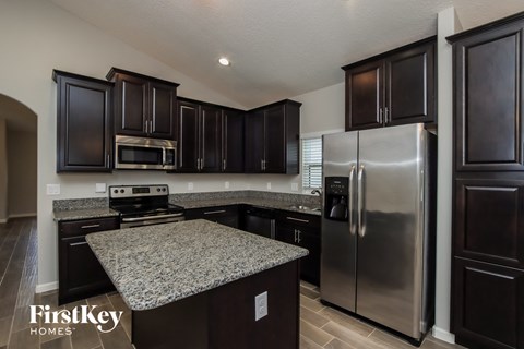 A kitchen with dark brown cabinets and a granite countertop.