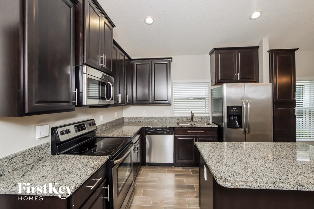 A kitchen with dark brown cabinets and granite countertops.