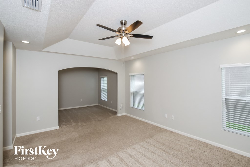 A spacious room with a ceiling fan and a carpeted floor.