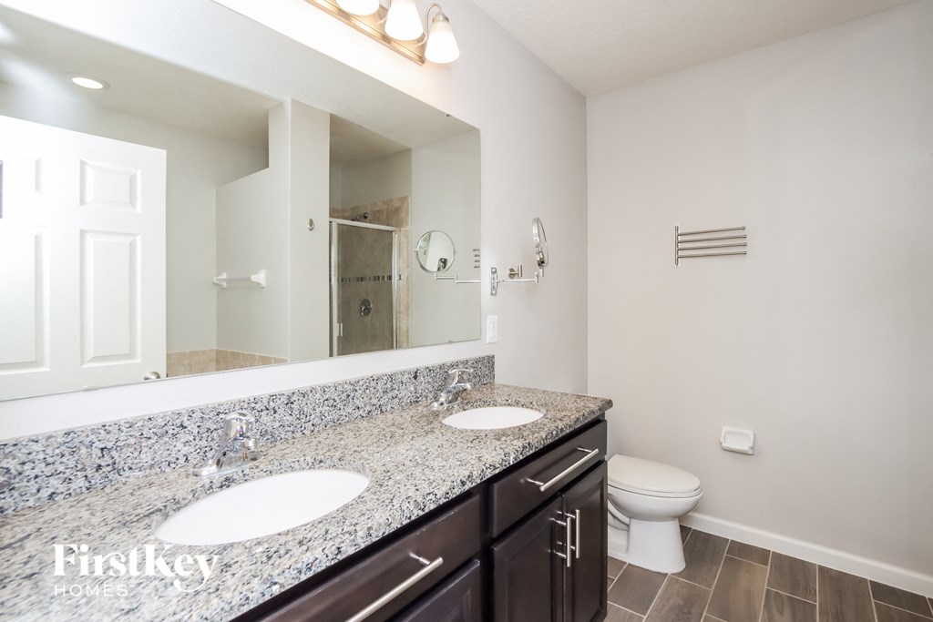 A bathroom with a granite countertop and a toilet.