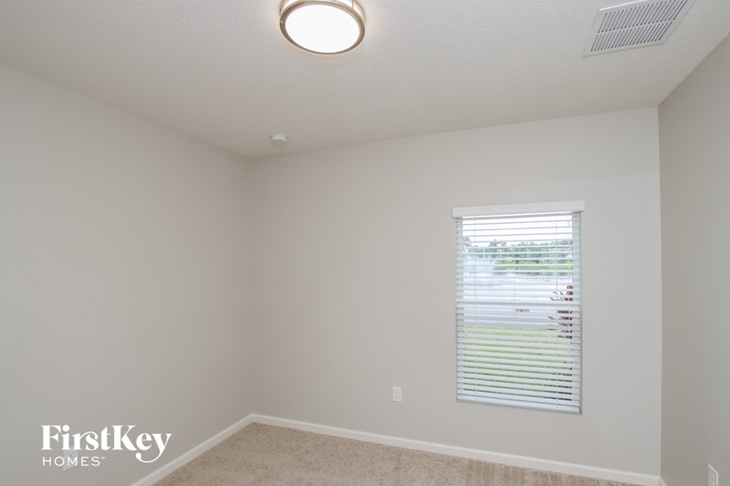 A room with a window covered by white blinds.