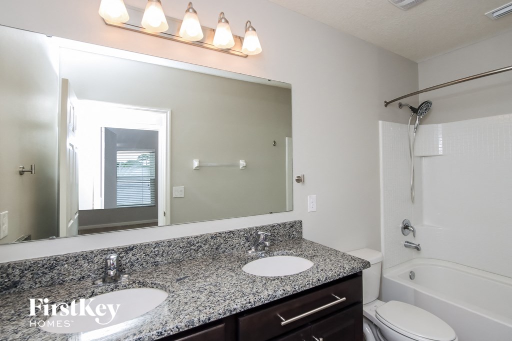 A bathroom with a granite countertop and a large mirror.