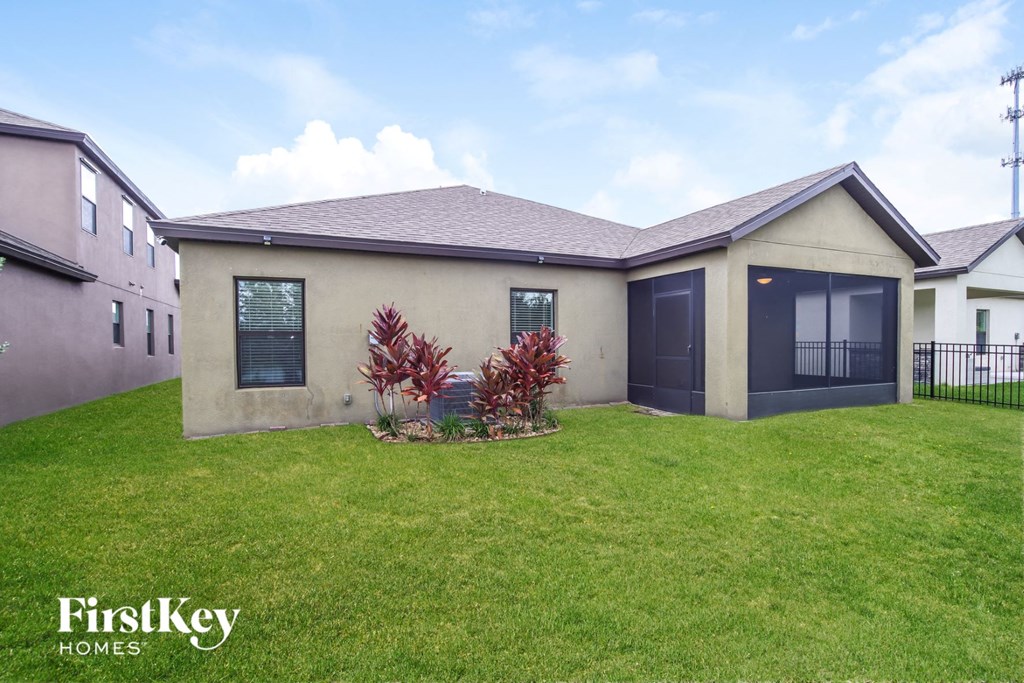 A house with a lawn and a fence in front of it.