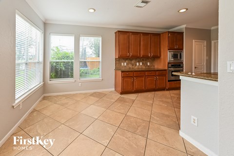 A kitchen with brown cabinets and a tile floor.