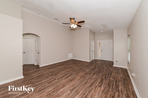 the living room of an empty house with a ceiling fan