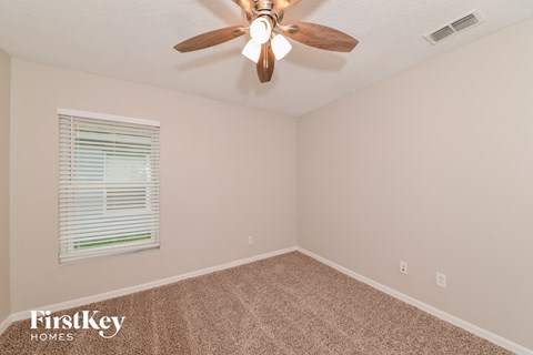 the bedroom has a ceiling fan and beige carpet