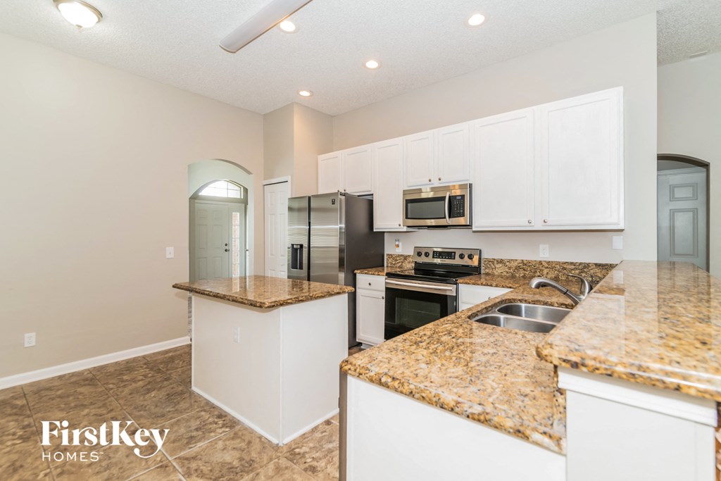 a kitchen with white cabinets and granite counter tops