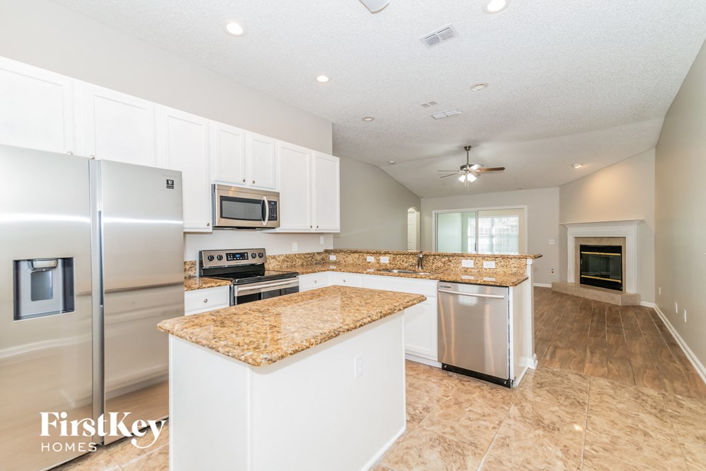 a kitchen with white cabinets and granite counter tops and stainless steel appliances
