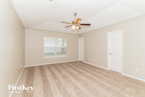 a spacious living room with carpet and a ceiling fan