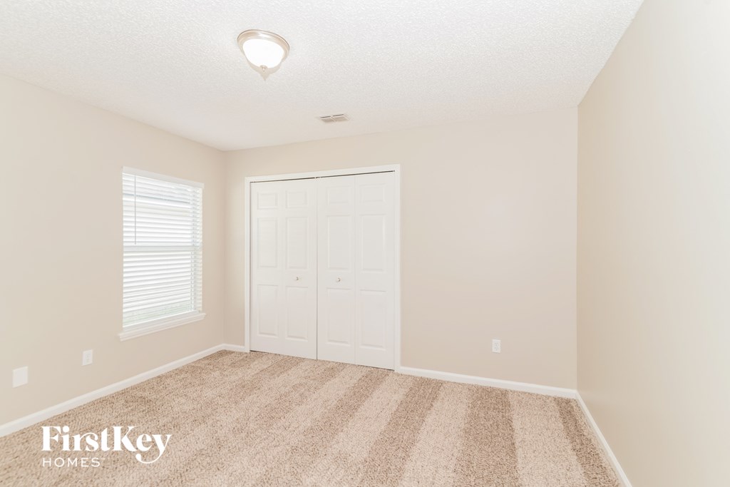 a bedroom with a closet and a door and a carpeted floor