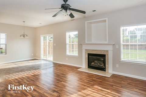 an empty living room with a fireplace and a ceiling fan