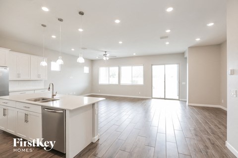 A spacious kitchen with white cabinets and a wooden floor.