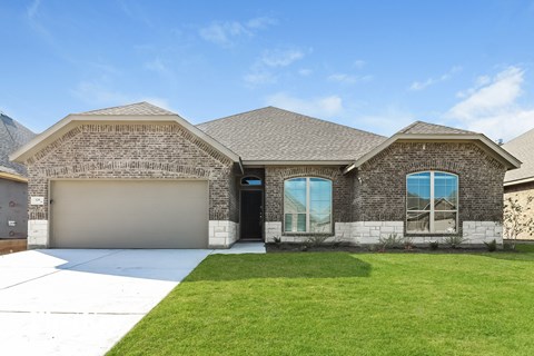 a brick house with a garage door and a lawn