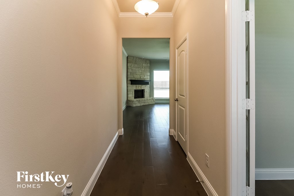 a hallway with a door to a living room and a fireplace