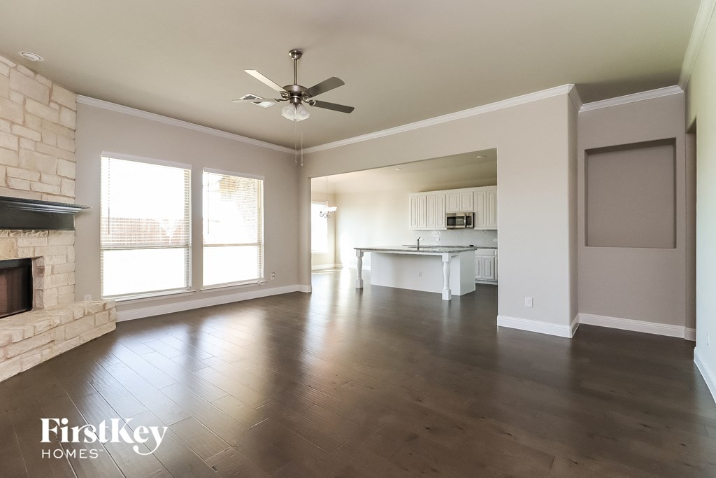 an empty living room with a fireplace and a ceiling fan