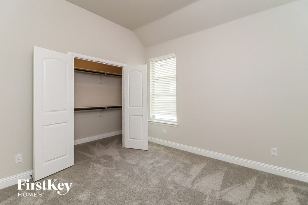 a room with a closet and an open door and a window