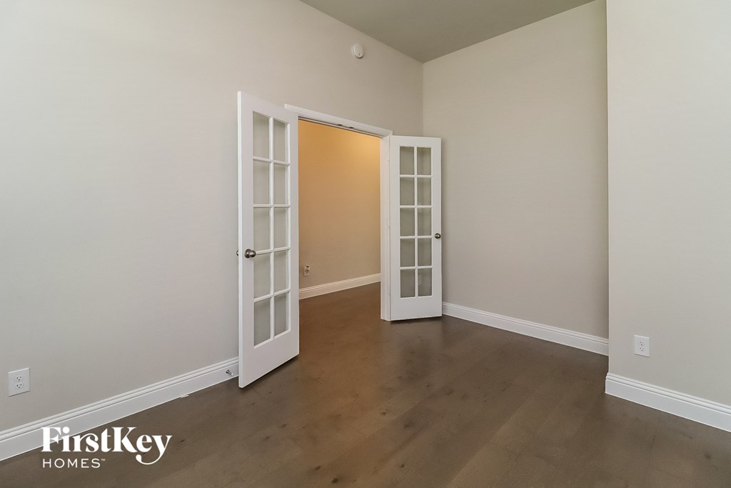the living room of a house with white doors and a wooden floor