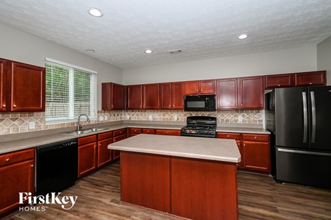 a kitchen with wooden cabinets and black appliances and a white counter top