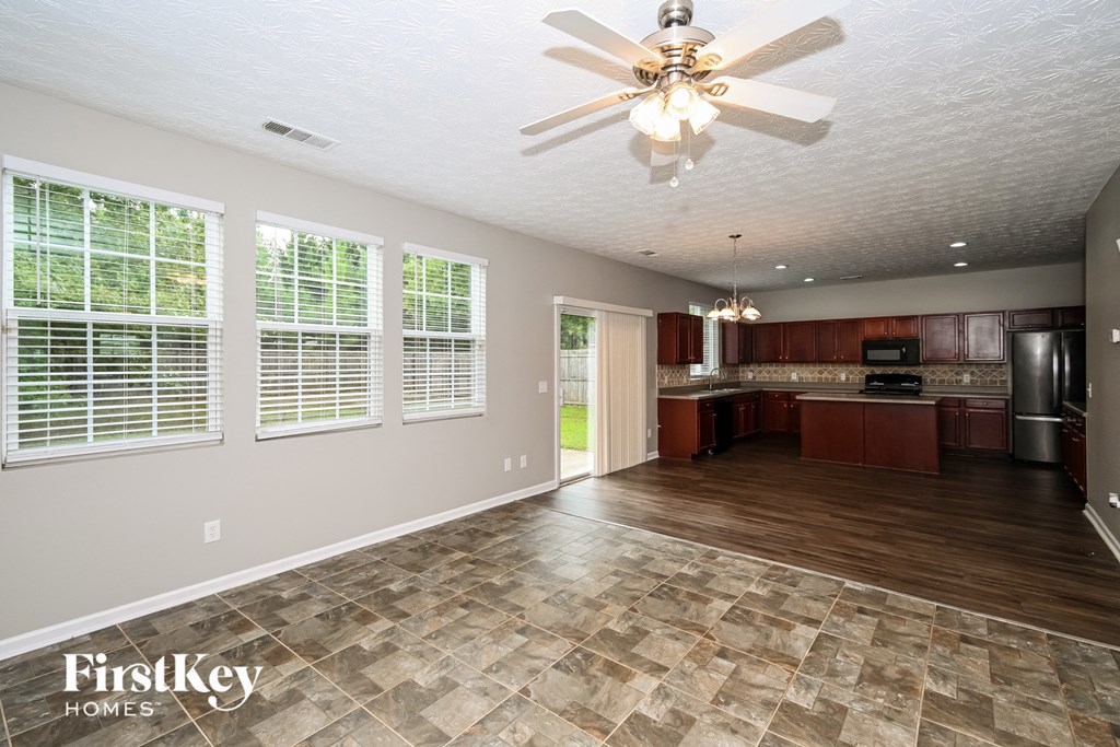 an empty living room and kitchen with a ceiling fan