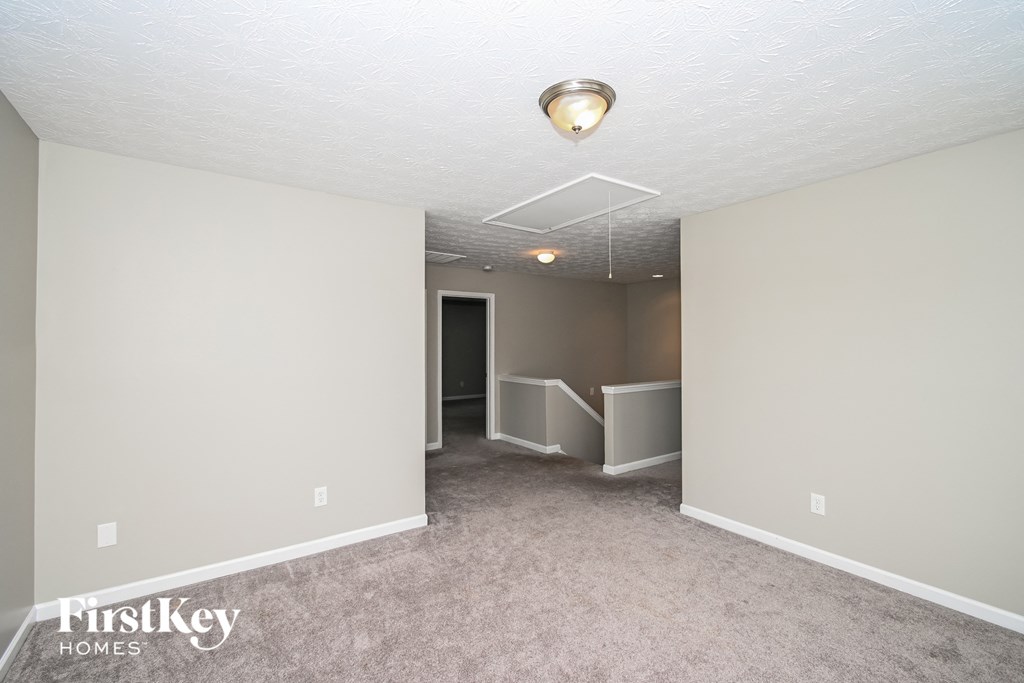 the living room and dining room of an apartment with carpeting and a ceiling fan