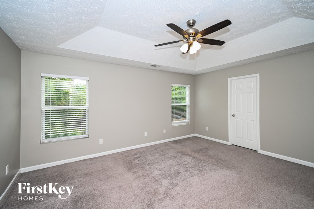 the master bedroom has a carpeted floor and a ceiling fan