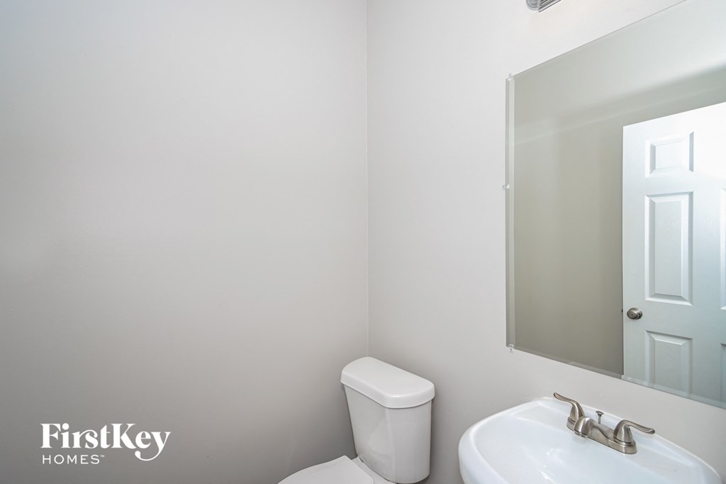 a white bathroom with a mirror and a toilet and a sink