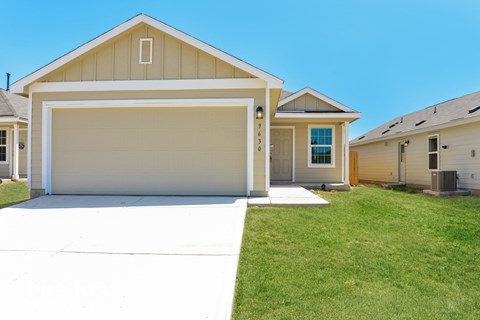 a beige house with a garage door and a green lawn