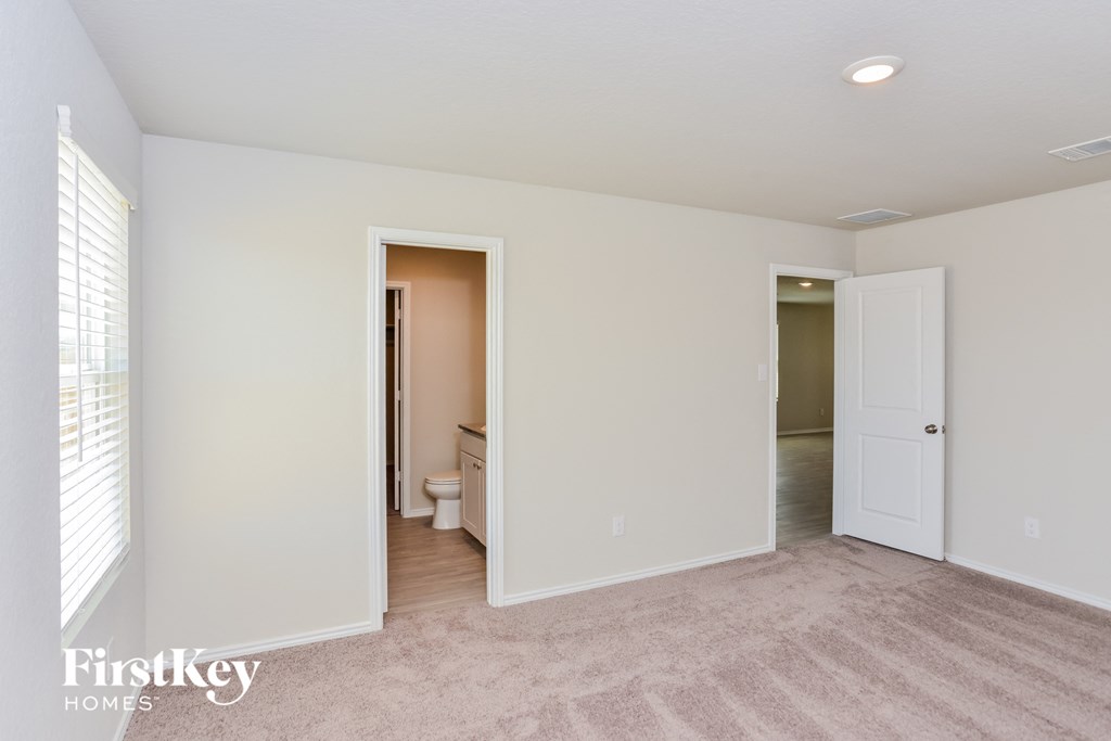 a bedroom with white walls and a door to a bathroom