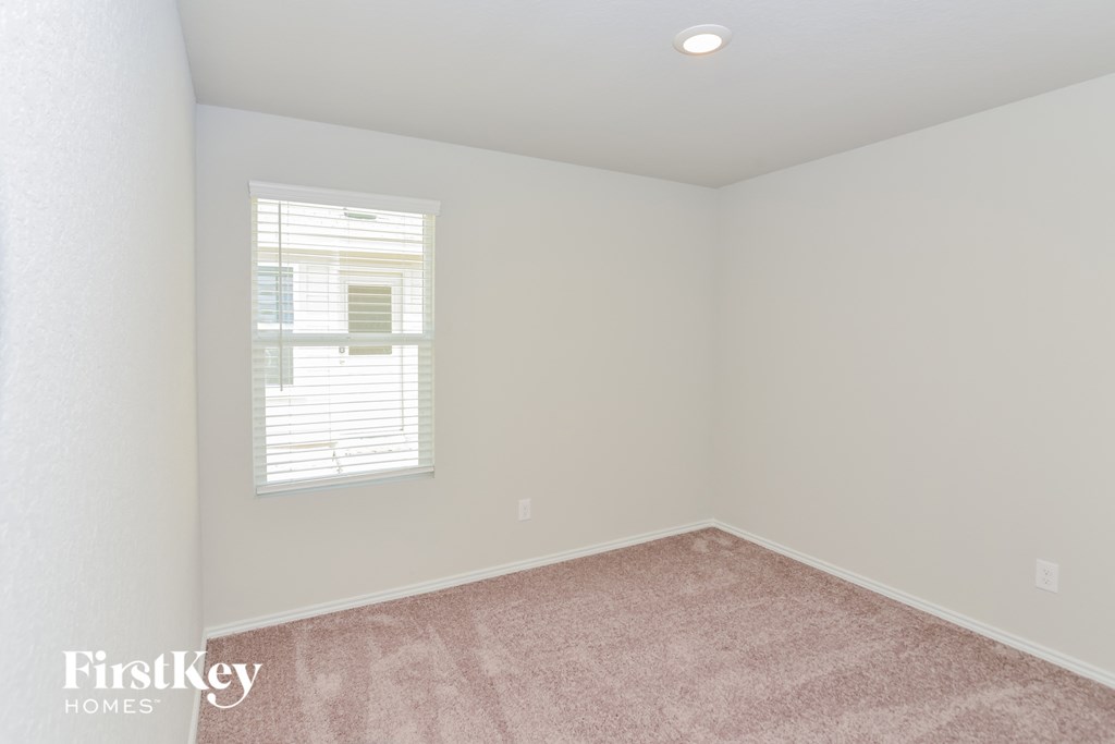 a bedroom with white walls and carpet and a window