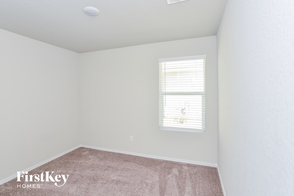 a bedroom with white walls and a window and carpet