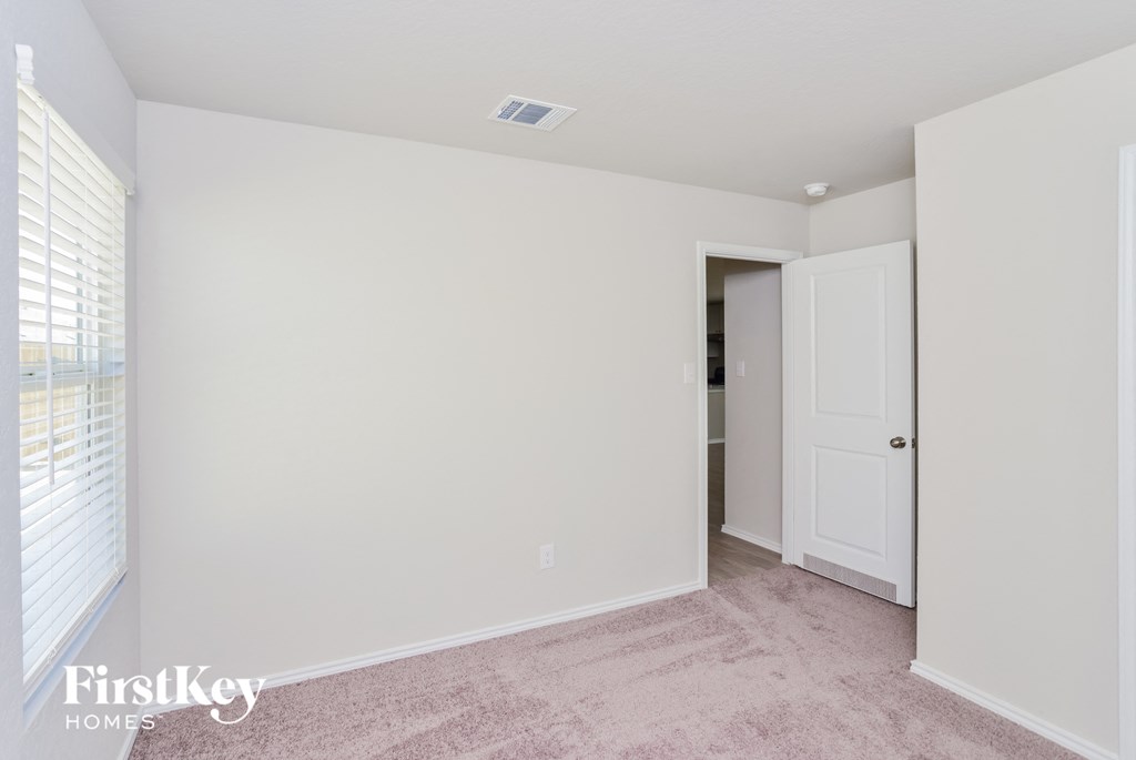 a bedroom with white walls and a door to a closet