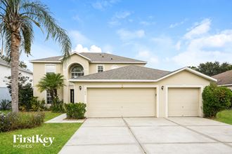 a yellow house with a garage and a palm tree