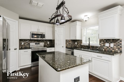 a kitchen with white cabinets and granite counter tops