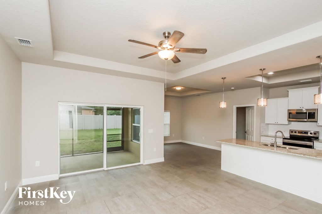 A spacious kitchen and living room with a ceiling fan and pendant lights.