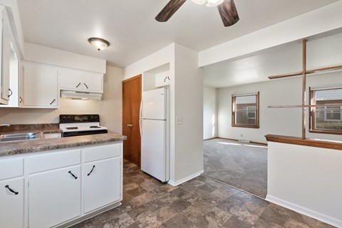 an empty kitchen with white cabinets and a white refrigerator