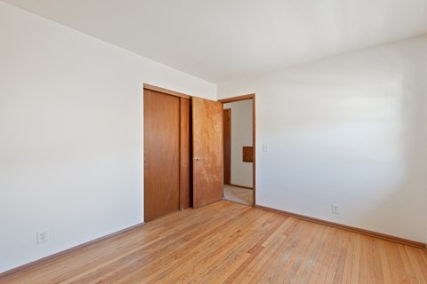 a living room with wood floors and white walls and a wooden door
