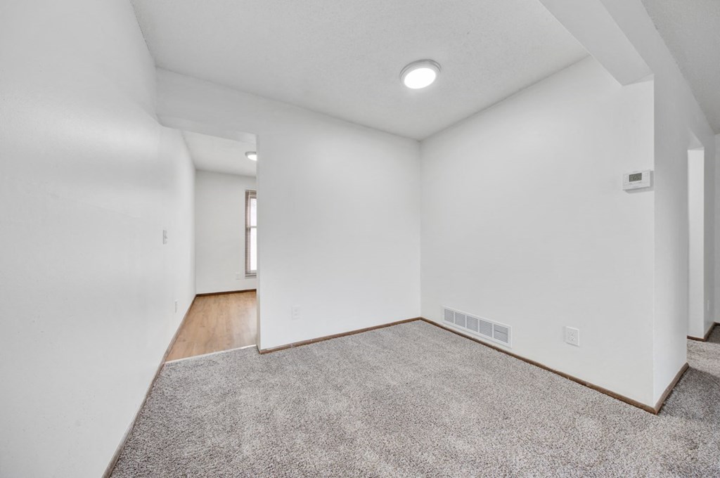 an empty living room with white walls and a carpet