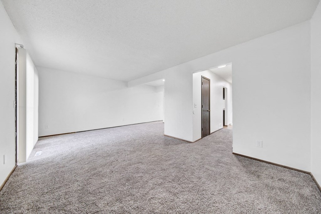 an empty living room with white walls and carpet