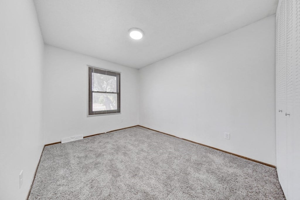 an empty living room with carpet and a window
