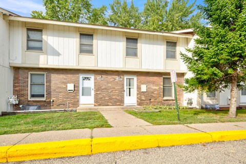 the front of an apartment building with a sidewalk and grass