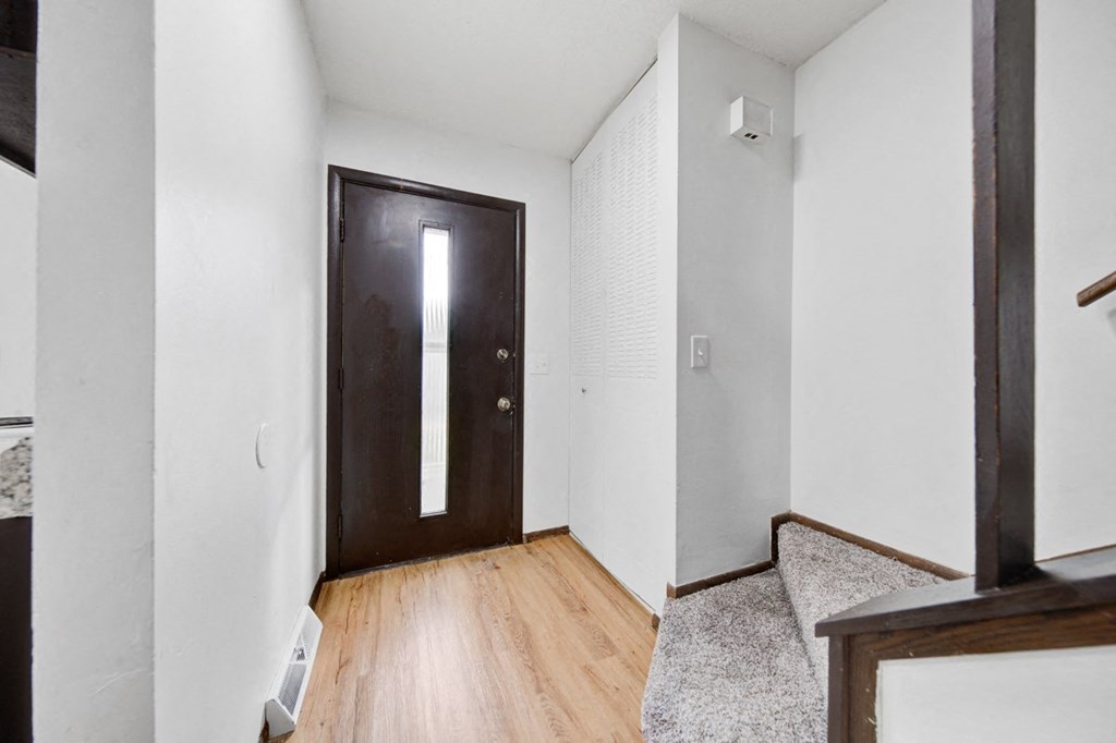 a wooden door in a room with white walls and wood floors