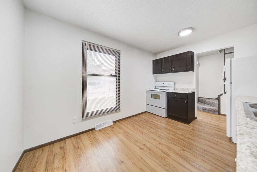 the living room and kitchen of an apartment with wood flooring and a window