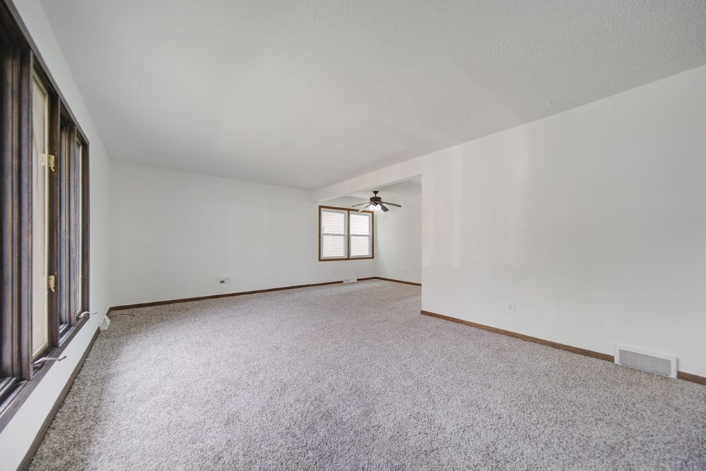 an empty living room with a window and a ceiling fan