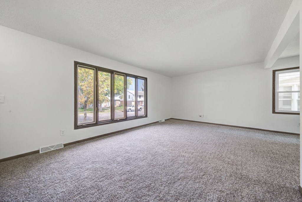 an empty living room with a large window and carpet