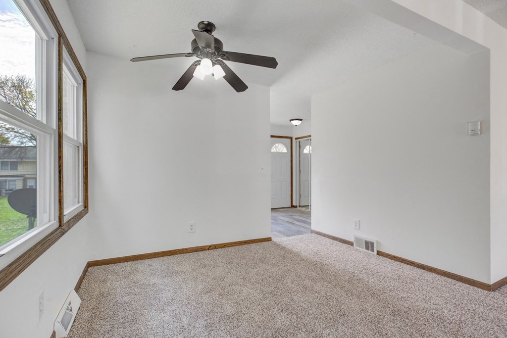 an empty living room with a ceiling fan and a window