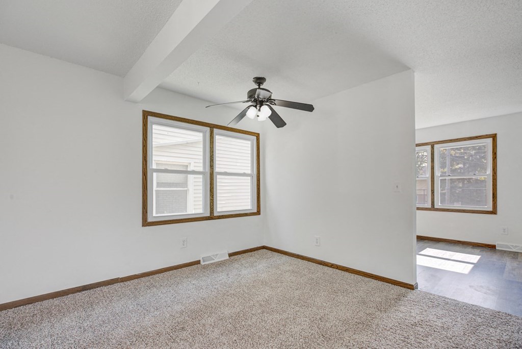 an empty living room with a ceiling fan and a window