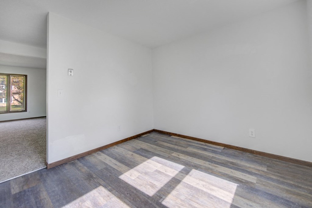 the living room of a home with white walls and wood floors