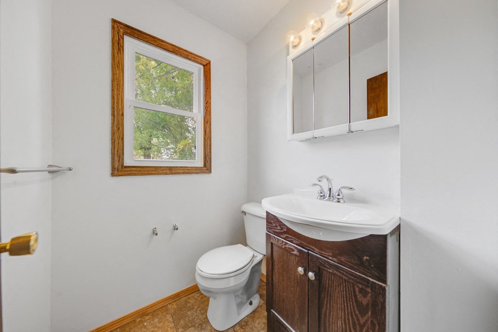 a bathroom with a toilet and a sink and a window