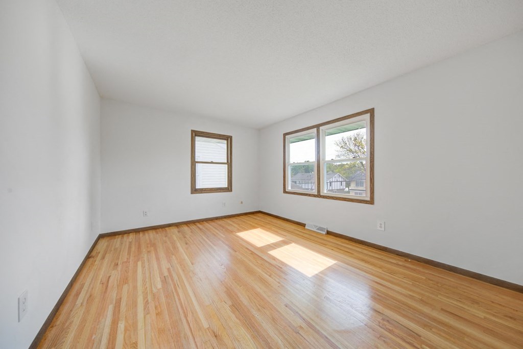 an empty living room with wood floors and a window