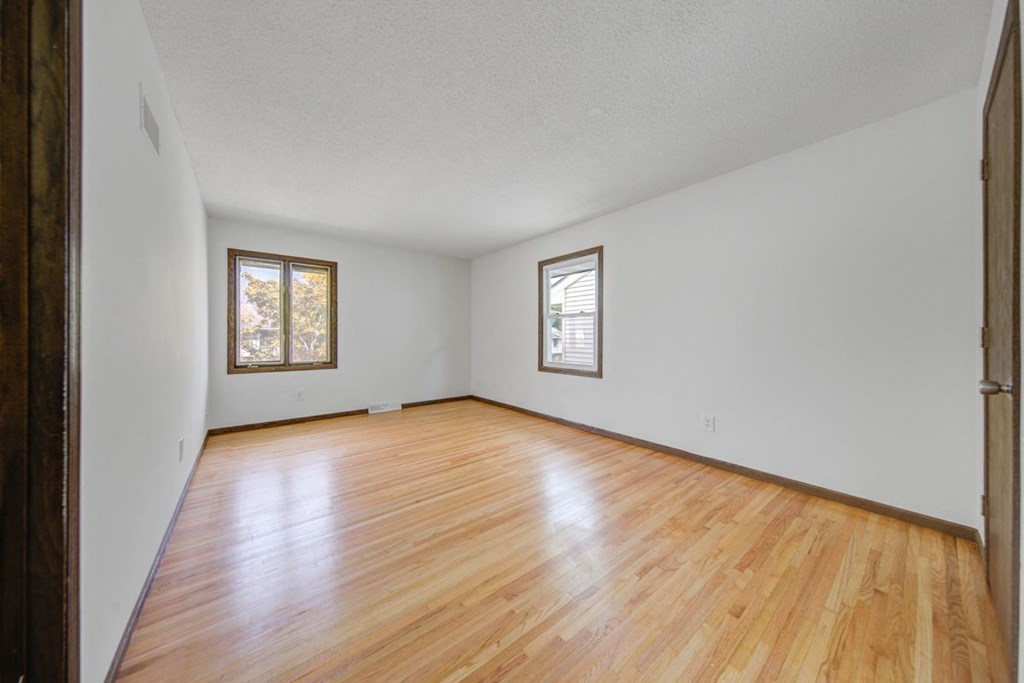 an empty living room with wood floors and white walls